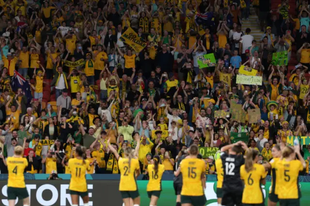 Matildas applaud the fans in the stands from the pitch.