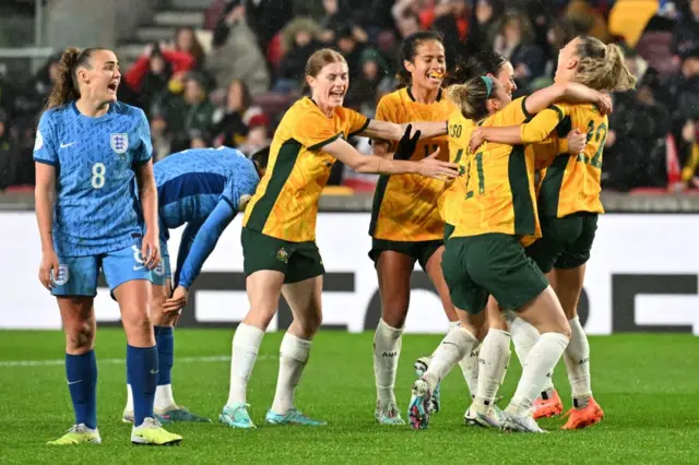 Georgia Stanway stands angry as Australia celebrate scoring.