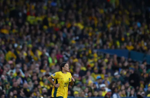 Sam Kerr jogs with the sea of fans behind her.