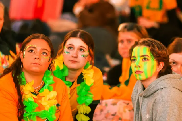 Australia fans watch the build up to the game in the fan park decked in green and gold.