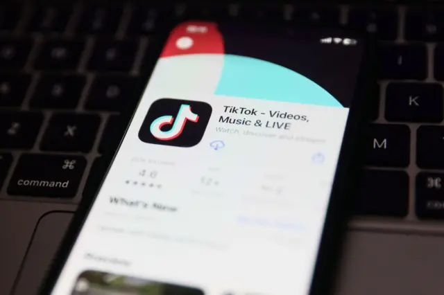 A laptop keyboard and TikTok on App Store displayed on a phone screen in the background are seen in this illustration photo