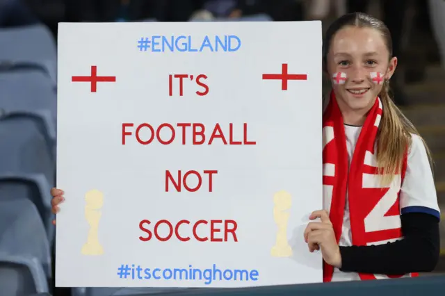 An England fan holds up a sign reading 'it's coming home, football not soccer'