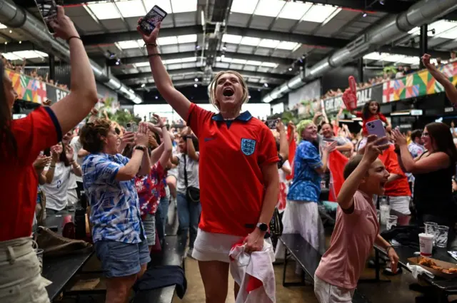 England fans celebrate the victory of England as they watch a screen showing the Women's World Cup semi-final football match between Australia and England, at Boxpark Wembley