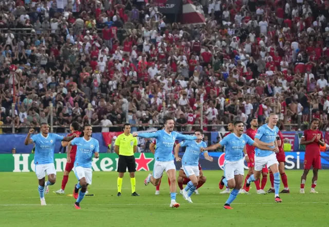 Manchester City players run in a group and celebrate