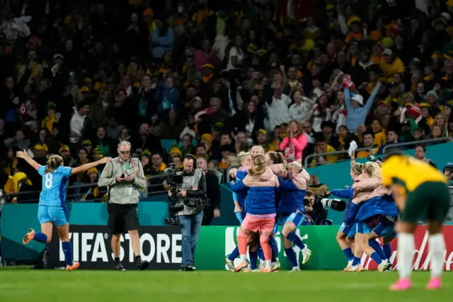 Sam Kerr stands on her haunches as England celebrate their third.