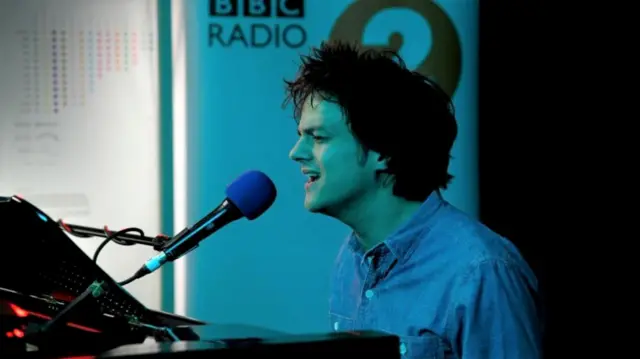 Jamie Cullum playing a piano and singing