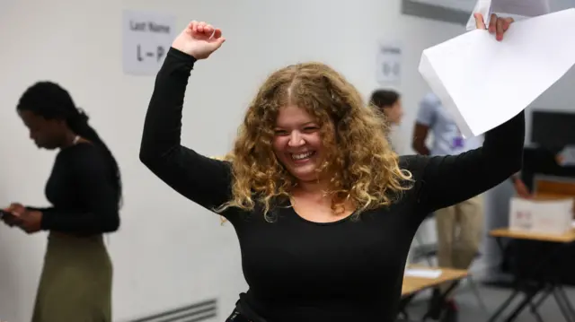 Ella holds her hands above her head in celebration