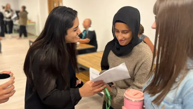 Student Iman shows her results to a friend