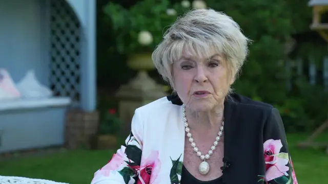 Gloria Hunniford talking into camera in a garden