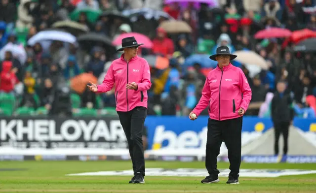 Umpires Roland Black (left) and Mark Hawthorne order the players off the field due to rain