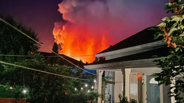 Fire can be seen over the rooves of houses