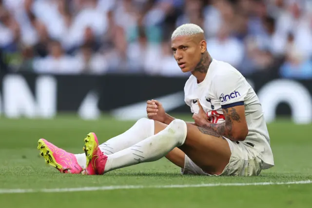 Richarlison sits on the turf after being dumped on the floor.