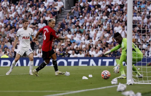 Davies fires the ball into the bottom corner as Martinez and Onana watch on.