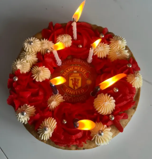 A birthday cake adorned with the united logo and colours.