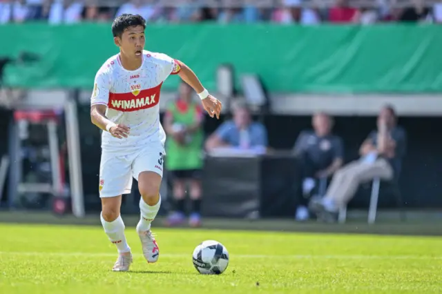 Wataru Endo runs with the ball in midfield for Stuttgart.