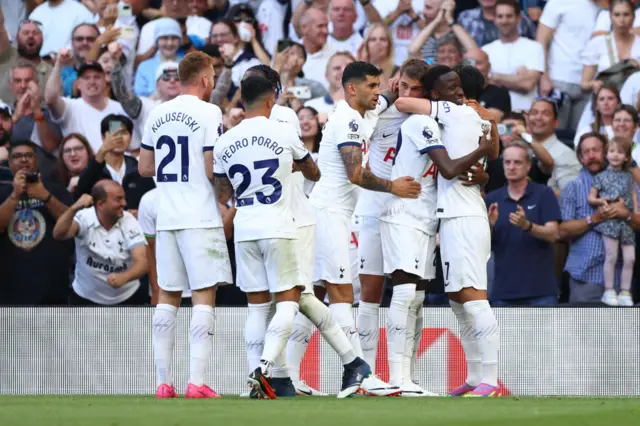 Spurs players gather around Sarr to celebrate his goal.