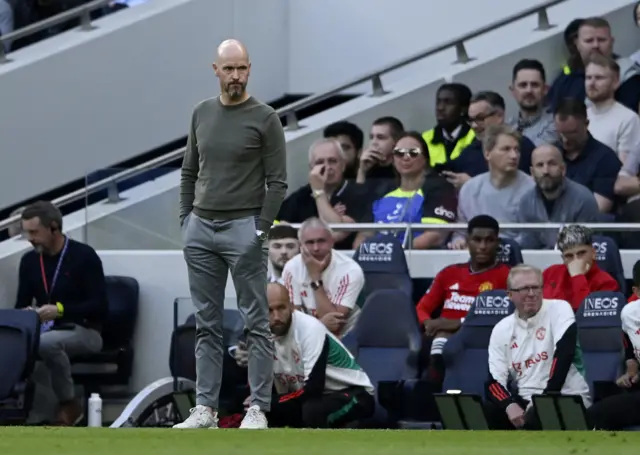 Erik ten Hag stands with his hands in his pockets with a concerned look on his face.