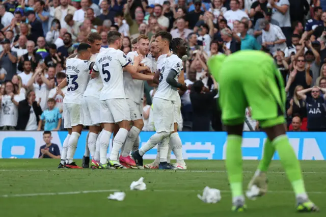 Onana stands on his haunches as Tottenham celebrate their goal.