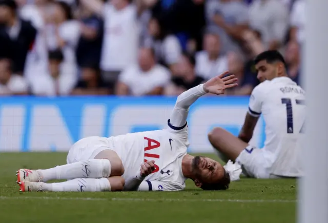 Maddison lies on the floor holding his leg, Romero also lies on the floor in the background.