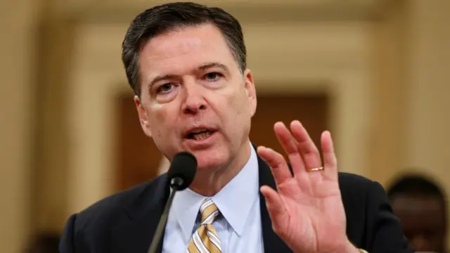 Comey raises a hand in gesture