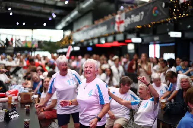 Two older fans smile and laugh as they sing Lionesses songs at Box Park.