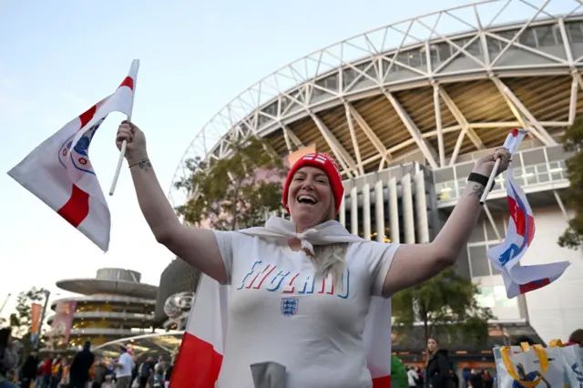 A fan waves England flags whiel wearing an England shirt outside the stadium.