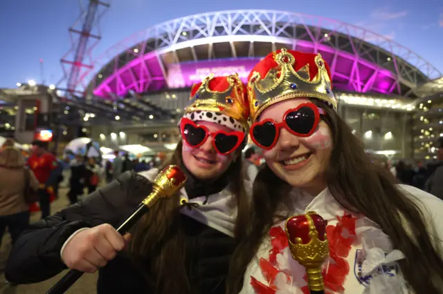 Fans with crowns and England fans arrive at the stadium.