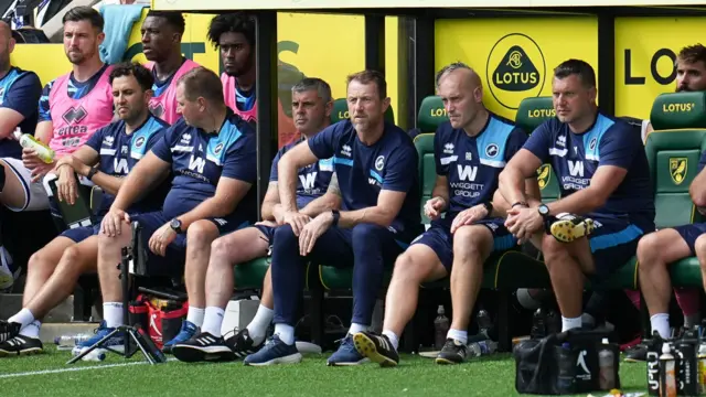 Millwall's coaching staff look on from the dugout