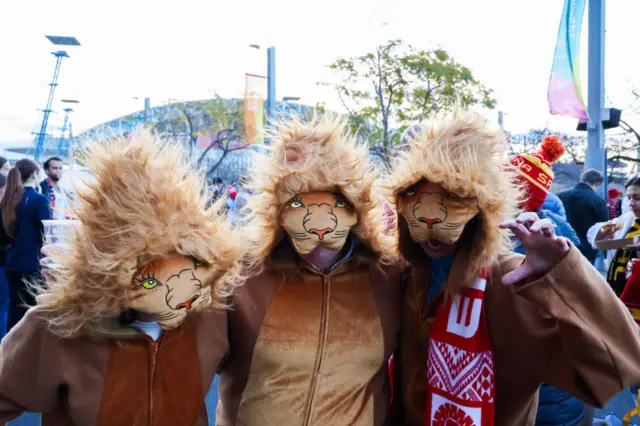 Three fans in lion costumes arrive at the stadium.