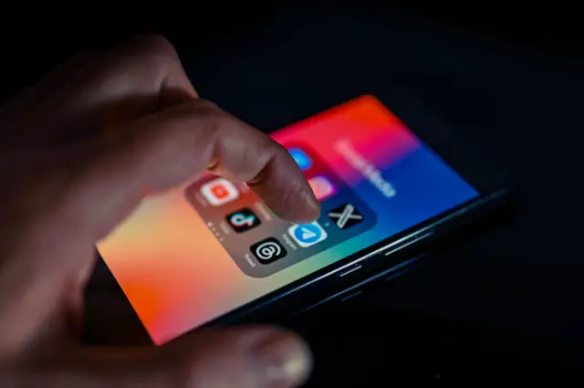 Close - up finger pointing to Telegram mobile app displayed on a smartphone screen alongside that of Facebook, X,TikTok,Threads. On 15 August 2023 in Brussels