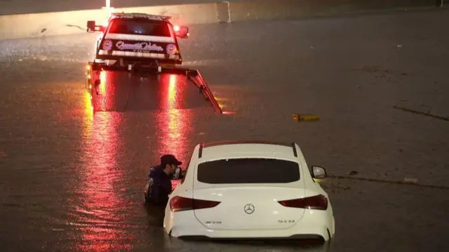 A tow truck driver attempts to pull a stranded car out of floodwaters on the Golden State Freeway as tropical storm Hilary moves through the area on August 20, 2023