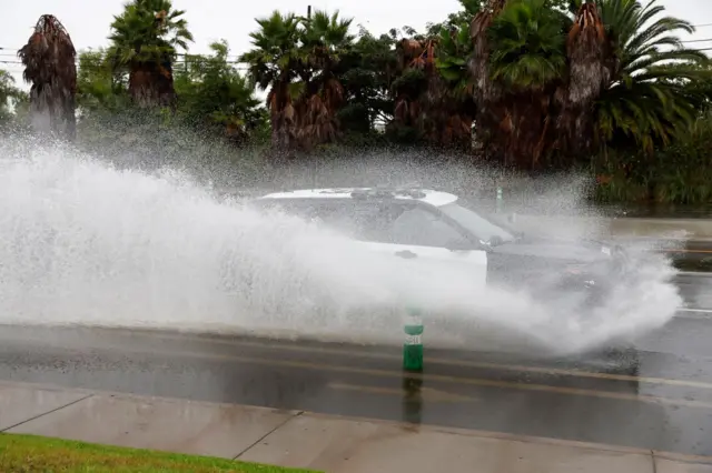 A car drives through standing water on a road in Long Beach, California. Photo: 20 August 2023