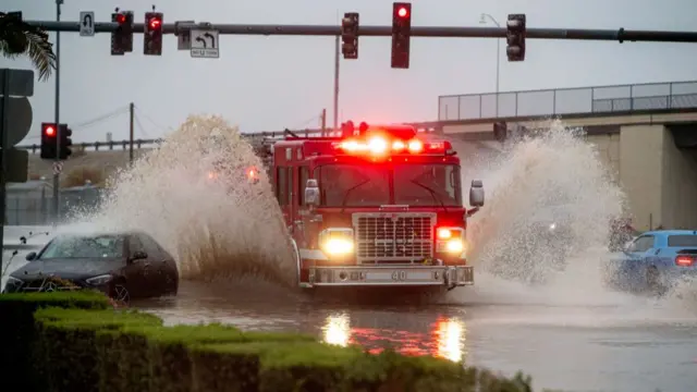 A Riverside County fire engine blasts through flood waters creating rooster tails which cover two cars stuck in the flood water on Avenue 48 during tropical storm Hilary on August 20, 2023