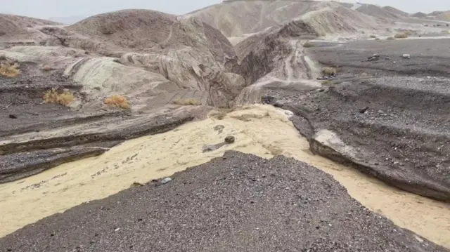 Floodwater flows through valleys in a dry landscape