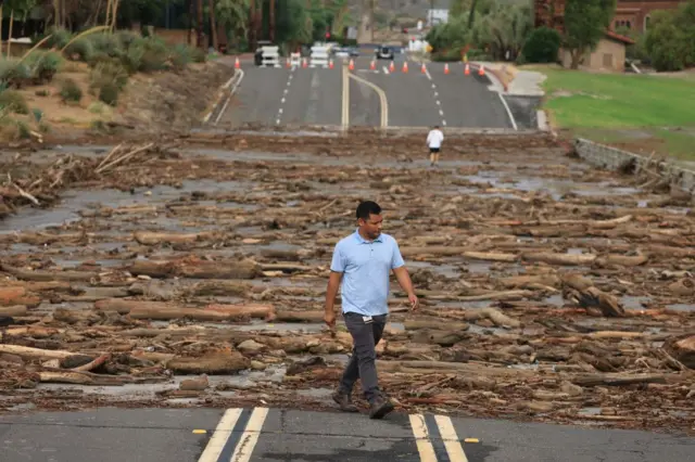 A worker from the Coachella Valley Water Department surveys the debris flow following heavy rains from Tropical Storm Hilary, at Thurderbird Country Club in Rancho Mirage, California,