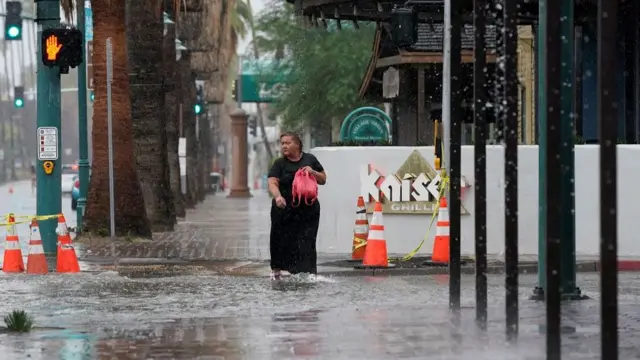 A woman walks through standing water as Tropical Storm Hilary approaches Palm Springs, California, U.S., August 20, 2023. REUTERS/Bryan Woolston