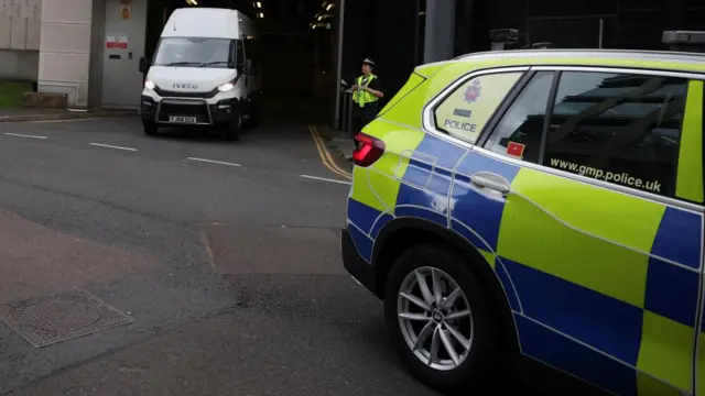 A Greater Manchester Police car leads the prison van out of Manchester Crown Court