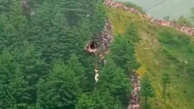 An aerial shot of a person dangling from a cable car