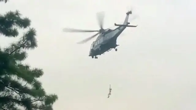 A helicopter rescues a person following a cable car with students stranded mid-air in Battagram, Pakistan