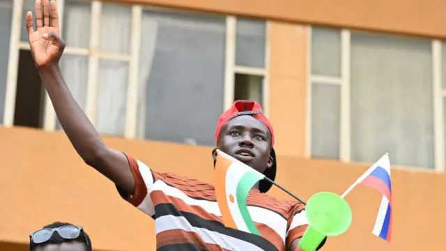 A supporter of the junta waves Nigerien and Russian flags in the capital, Niamey, on 13 August.