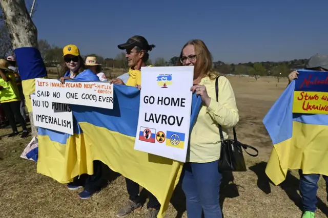 People hold signs telling Russian foreign minister, Sergei Lavrov, to go home to Russia.