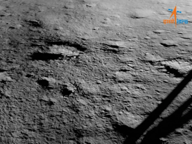 An image of the moon's surface with the spacecraft's leg visible in the bottom right corner