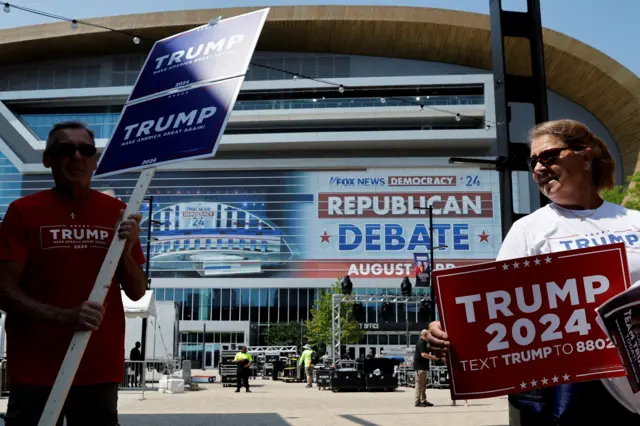 Supporters of Republican presidential candidate and former U.S. President Donald Trump walk around the arena with Trump campaign signs the day before the debate in Milwaukee, Wisconsin