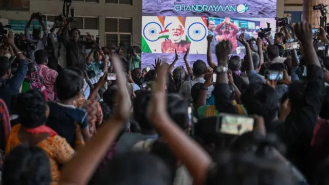 A view over peoples heads as they raise their hands in celebration