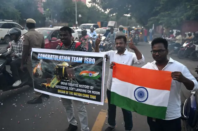 Men hold a banner that reads 'congratulations team Isro'