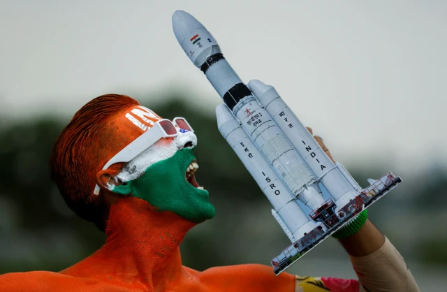 Arun Haryani, an enthusiast with his body painted in the colours of the Indian flag holds up a model of the rocket which was used in launching of Chandrayaan-3 spacecraft