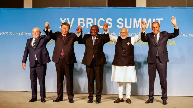 The five representatives hold hands, raising them above their heads