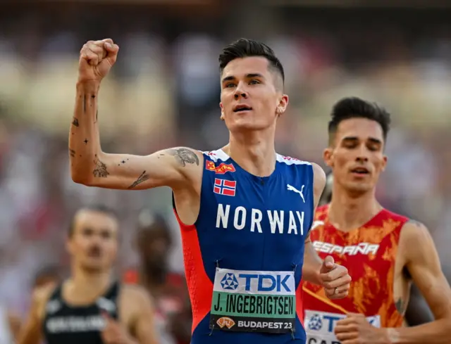 Jakob Ingebrigtsen celebrates winning a 1500m semi-final at the 2023 World Athletics Championships in Budapest, Hungary by clenching and raising his fist.