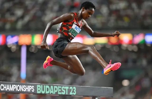 Jackline Chepkoech jumps over a hurdle