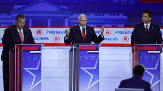 Former New Jersey Governor Chris Christie and Florida Governor Ron DeSantis listen as former U.S. Vice President Mike Pence speaks at the first Republican candidates' debate